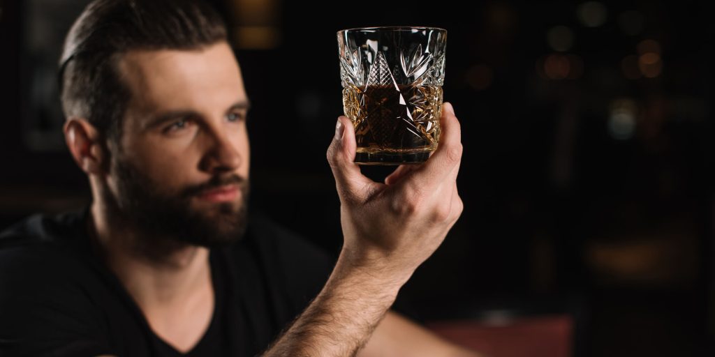 Man looking at a glass of whisky after alcohol detox in columbus ohio