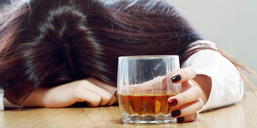 Woman holding her head down and holding a glass of alcohol before alcohol detox in columbus ohio