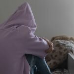 Young girl sitting on bed having suffered from trauma and at risk for addiction
