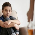 Boy sad on coach looking at the genetic affect alcohol has on his family