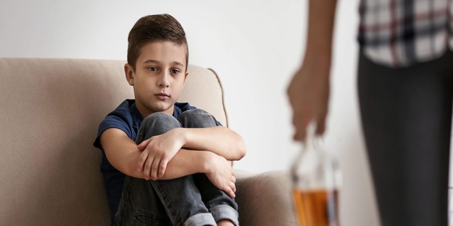 Boy sad on coach looking at the genetic affect alcohol has on his family