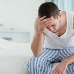man with addiction and weakened immune system feeling sick with his head on his hand